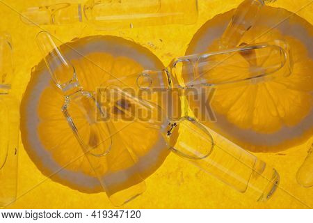 Vitamin C Transparent Ampoules Set And Lemon Slices On A Yellow Background. Prevention Of Immunity F