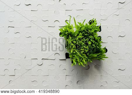 Background Of The Cardboard Puzzle Without Drawing. Bright Green Grass Grows Through The Hole, As If