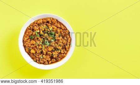 Keema Curry In Bowl Over Yellow Background With Copy Space. Indian And Pakistani Style Dish. Top Vie