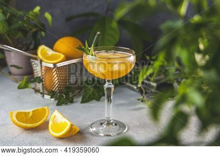 Champagne Coupe Glass Of Refreshing Orange Cocktail With Ice Served On Gray Table Surface Surround O