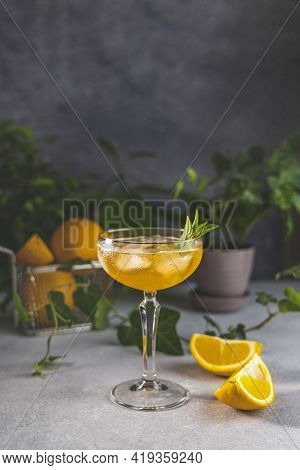 Champagne Coupe Glass Of Refreshing Orange Cocktail With Ice Served On Gray Table Surface Surround O