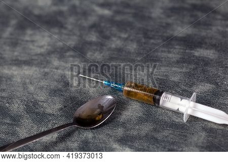 Drug Addiction Concept, Drug Syringe With Heroin And Cooked On Spoon On Gray Background With Copy Sp