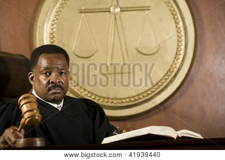 ผู้พิพากษาอเมริกันแอฟริกันถือตะลุมพุกใน courtroom