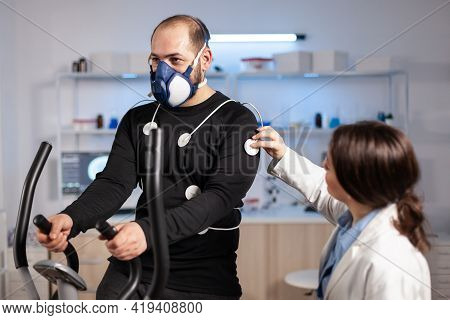 Man Athlete With Mask Running On Cross Trainer