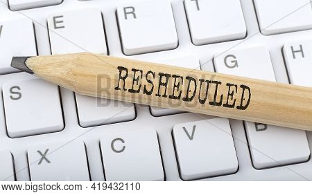 Text Resheduled On Wooden Pencil On White Keyboard. Business