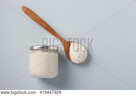 Vegan Organic Paste Of Coconut In Glass Jar As Well As Coconut Flour In A Wooden Spoon On A Light Bl