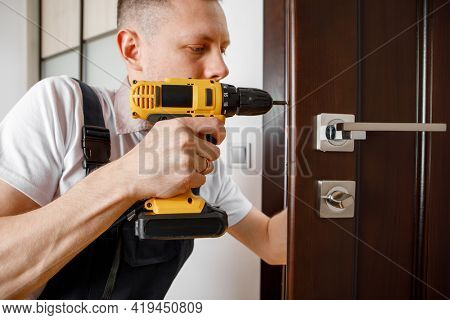 a man repairing a doorknob. Handyman repair the door lock in the room