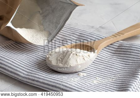 Crumbly Xanthan Gum In A Wooden Spoon.