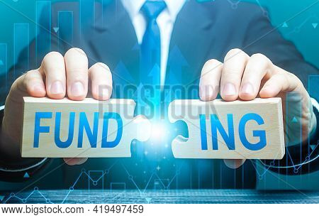Businessman Connects Puzzles With The Word Funding. Investing In A Business Project, Raising Funds. 