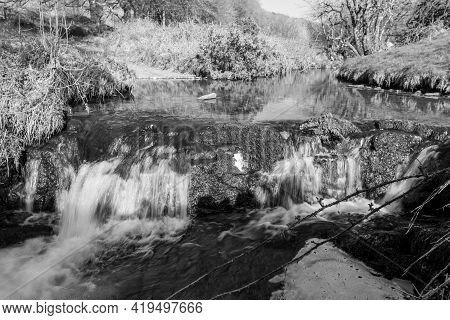 Long Exposure Of The Weir Water River  Flowing Through The Valley At Robbers Bridge In Exmoor Nation