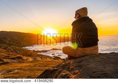 A Young Woman Relaxed At Sunset In The Cove Of Stones In The Jaizkibel Mountain In The Town Of Pasaj