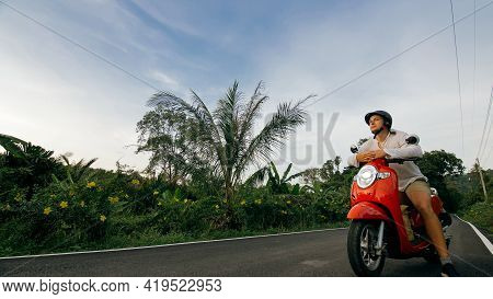 Man On Red Motorbike In White Clothes Drive On Forest Road Trail Trip. One Men Caucasian Tourist Go 