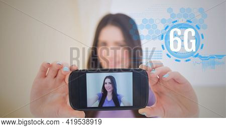 Composition of 6g text and data processing over woman holding smartphone with picture of herself. global networks, technology and digital interface concept digitally generated image.