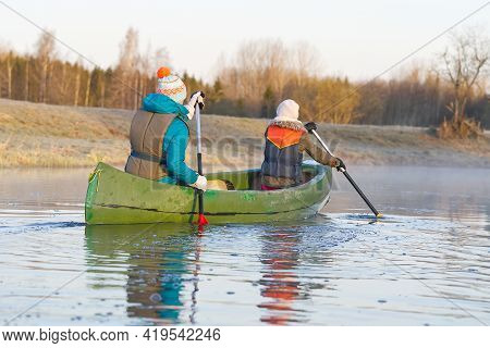 Mother And Daughter Rowing A Canoe In Early Spring In The Early Morning. Active Lifestyle. Morning L