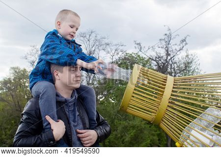 Dad And Son Throw The Plastic Bottle Into The Plastic Collection Container. Recycling And Disposal O