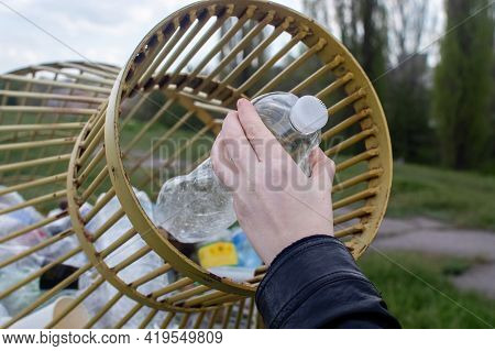 A Woman Tosses A Plastic Bottle Into A Plastic Container For Collection. Recycling And Disposal Of P