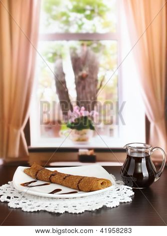 หวาน pancakes บนแผ่นกับนมข้นบนโต๊ะในห้อง