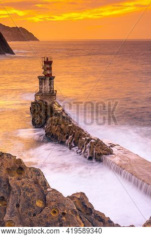 Long Exposure In The Orange Sunset At The Lighthouse In The Municipality Of Pasajes San Juan In Gipu