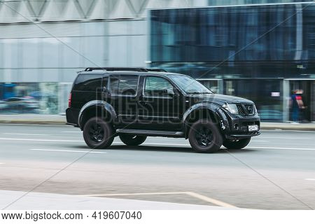 Fast Moving Old Nissan Pathfinder On The City Road. Black Suv Driving Down The Street. Used Auto In 