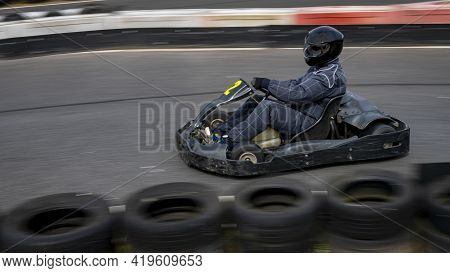 A Panning Shot Of A Racing Kart As It Circuits A Track.