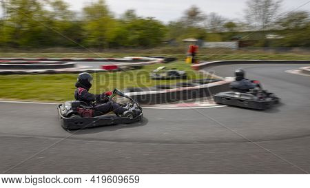 A Panning Shot Of A Racing Kart As It Circuits A Track.