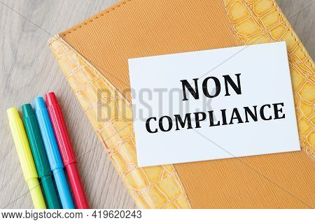 Card With Text Non Compliance On A Yellow Notepad On The Table Next To Markers