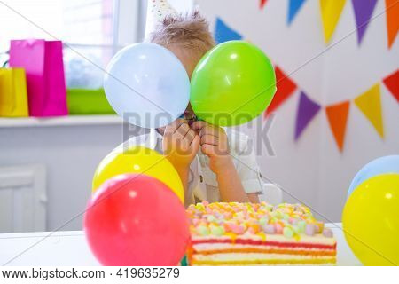 Birthday Boy Hid Behind Colorful Balloons Near Birthday Rainbow Cake. Festivel Background. Funny Bir