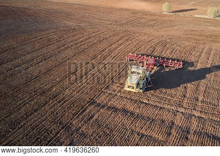 A Heavy Tractor Plows The Field. Shooting From A Drone. Copy Space.