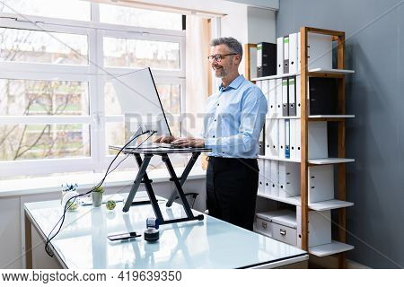 Large Version Of Adjustable Height Desk Stand In Office Using Computer