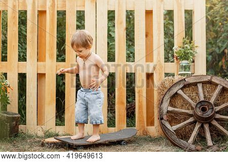 Pretty Cheerful Young Boy. Cute Little Child Are Skateboarding Outdoors. A Boy Training Inline Skati