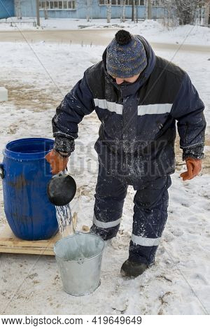 Worker Pours Water From A Barrel Into A Bucket
