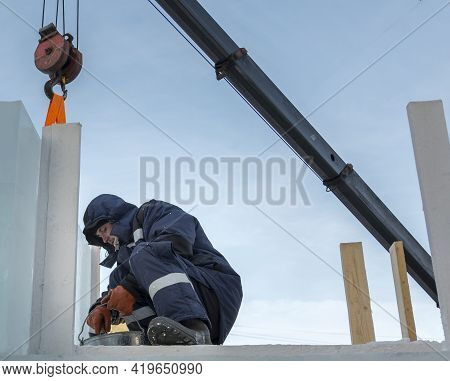 A Portrait Of A Fitter In A Blue Jacket At The Hook Of A Truck Crane