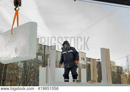 A Portrait Of A Fitter In A Blue Jacket At The Hook Of A Truck Crane