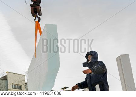 A Portrait Of A Fitter In A Blue Jacket At The Hook Of A Truck Crane