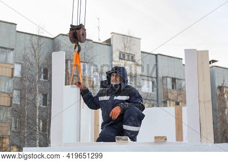 A Portrait Of A Fitter In A Blue Jacket At The Hook Of A Truck Crane