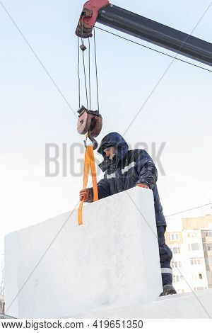A Portrait Of A Fitter In A Blue Jacket At The Hook Of A Truck Crane