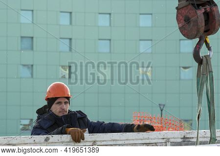 A Portrait Of A Fitter In A Blue Jacket At The Hook Of A Truck Crane