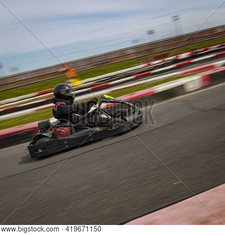 A Panning Shot Of A Racing Kart As It Circuits A Track.