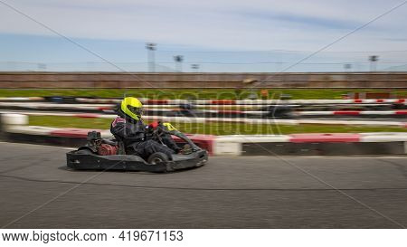 A Panning Shot Of A Racing Kart As It Circuits A Track.