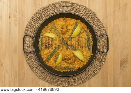Top View Image Of Rice With Chicken And Valencian Vegetables Inside A Paella Pan On A Wooden Table A