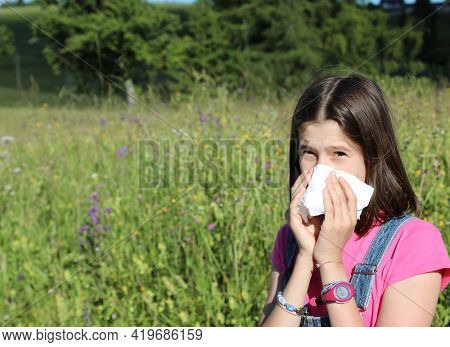 Young Girl Allergic To Pollen While Blowing Her Nose In The Middle Of The Meadow In Spring