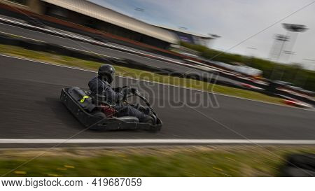 A Panning Shot Of A Racing Kart As It Circuits A Track.