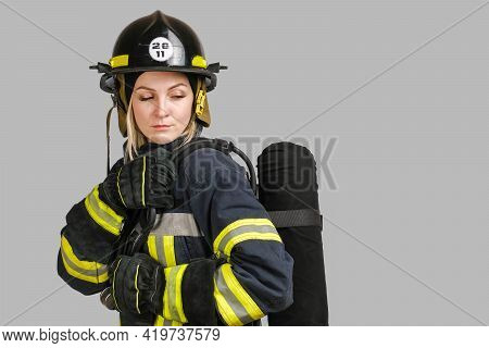 Young Caucasian Woman In Uniform Of Firefighter Posing In Profile With Air Tank On Her Back Isolated