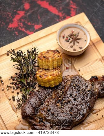 Grilled Juicy Steak With Vegetables On A Wooden Cutting Board. Cooked Meat With Mixture Of Pepper, C