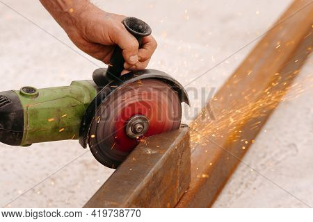 Cutting A Metal Pipe With A Splash Of Spark. The Pipe Is Clamped In A Vice. Man's Hands Hold A Grind
