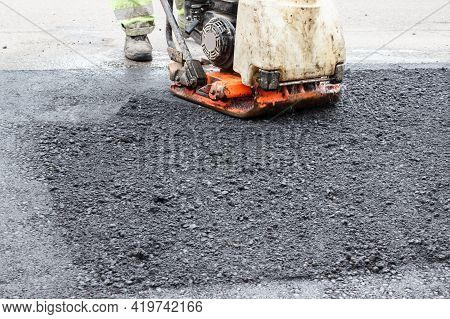 Worker Ramps The Asphalt On The Road With A Mechanical Rammer. Laying The Road Surface. Hot Asphalt 