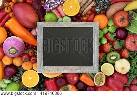 Plant based healthy natural antioxidant food with fruit and vegetables that neutralise free radicals also high in fibre, anthocyanins, lycopene, vitamins, and carotendoids. Copy space on blackboard.