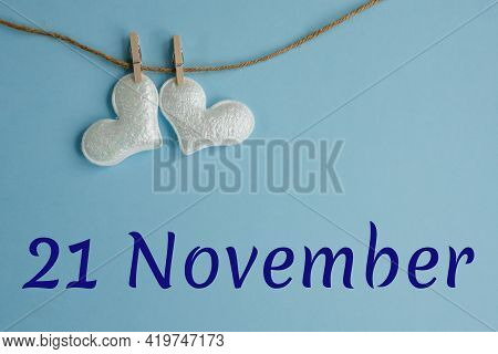 Commemorative Date November 21 On Blue Background With White Hearts With Clothespins, Flat Lay. Holi