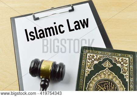 Top View Of Holy Quran, Judge Gavel And White Paper Written With Islamic Law.