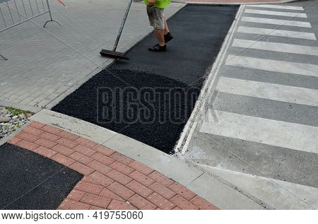 An Asphalt Repair Worker With Hot Black Material Aligns The Holes After The Excavation Work At The P